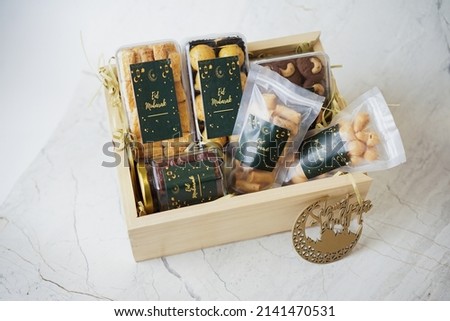 Ramadhan gift. Hampers moslem theme for celebrete the holy, bake snack, nastar, bakery, cookies, pudiing, chococips, roll cake, castangel.with greeting card and green accessories on white background Royalty-Free Stock Photo #2141470531