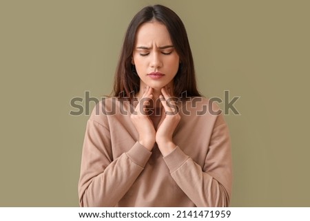 Young woman suffering from sore throat on color background