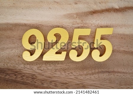 Wooden  numerals 9255 painted in gold on a dark brown and white patterned plank background.