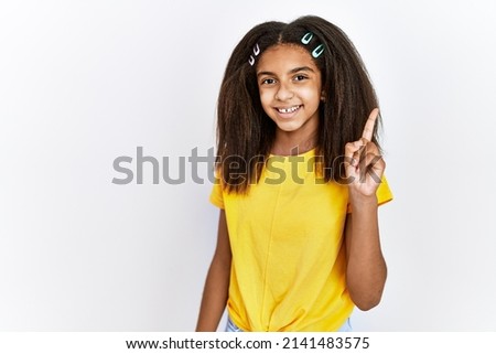 Young african american girl standing over white isolated background showing and pointing up with finger number one while smiling confident and happy. 