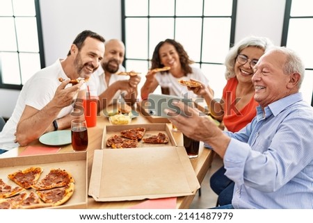 Group of middle age people smiling happy eating italian pizza make selfie by the smartphone at home