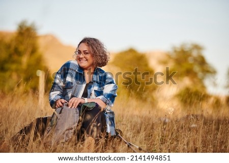 The woman is resting from hiking in nature and searching for her backpack. Selective focus. High-quality photo