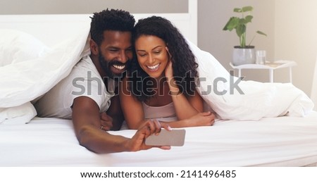 I appreciate everyday with you, lets take a selfie. Cropped shot of a young attractive couple taking a selfie in bed at home.