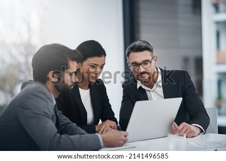 Theyre a team that gets things done. Shot of three businesspeople gathered around a laptop in the boardroom. Royalty-Free Stock Photo #2141496585
