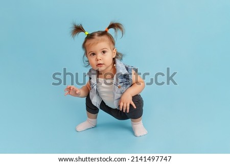 Portrait of Funny little girl with two ponytails in a fashionable denim jacket. Little fashion-girl. Happy childhood and trendy children wear concept. Child fashion. Isolated on blue background. Royalty-Free Stock Photo #2141497747