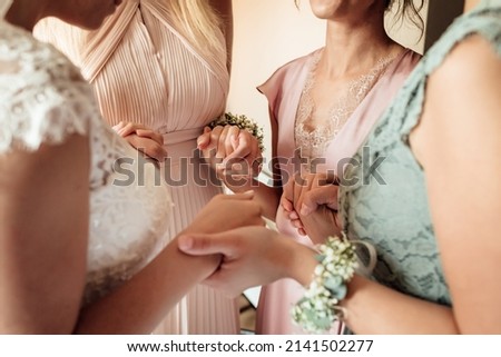 Morning of bride. Gorgeous bride with best bridesmaids are holding hands in hotel room. Wedding morning details. High quality photo. Royalty-Free Stock Photo #2141502277