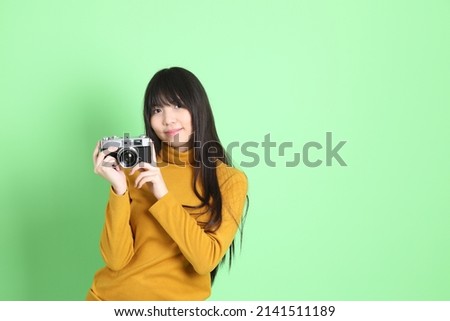 The cute young Asian girl with casual dressed standing on the green background