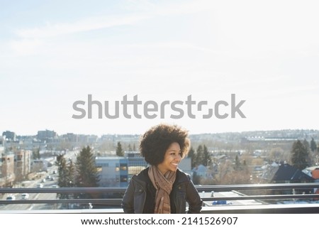 Smiling woman looking away on patio against cityscape