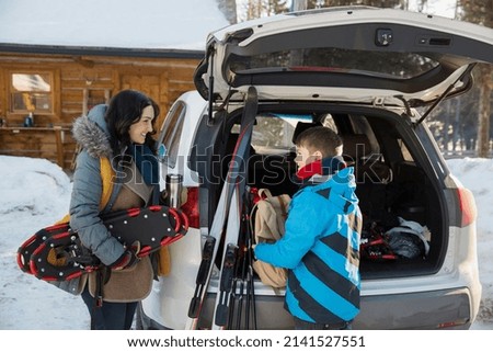 Mother and son unloading winter sports gear from car