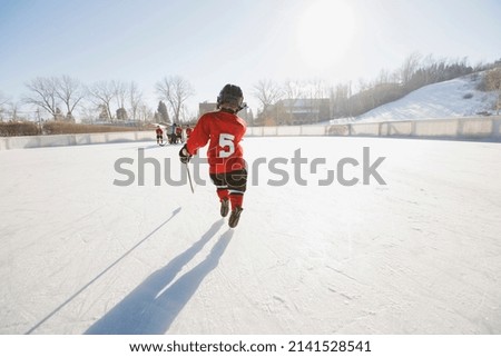 Rear view of ice hockey player skating on rink