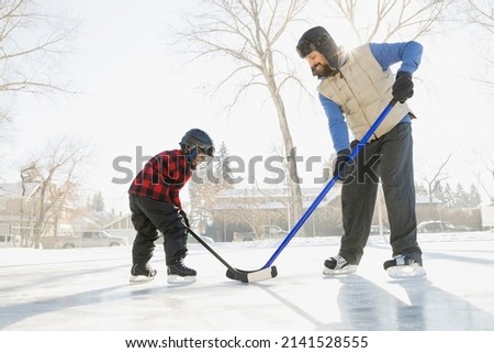 Father and son playing ice hockey