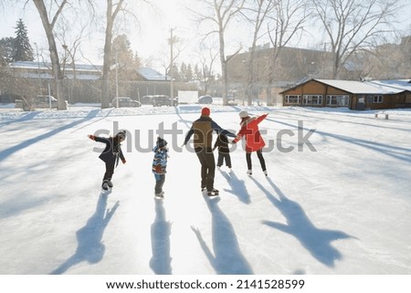 Family ice-skating on outdoor rink together