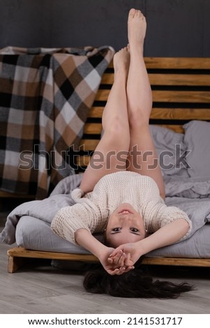 Smiling cheerful beautiful pretty ukrainian woman posing in warm knitted sweater. Girl feeling relaxing and enjoy time on the bed at home.