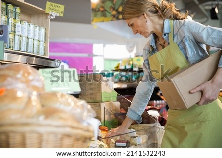 Worker stocking cheese in market