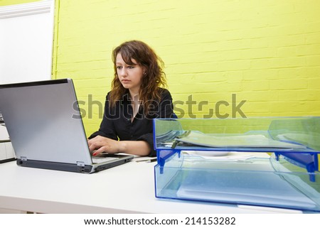 Caucasian young woman working on her laptop computer at her desk