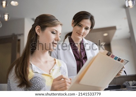 Dentist and receptionist reviewing medical records