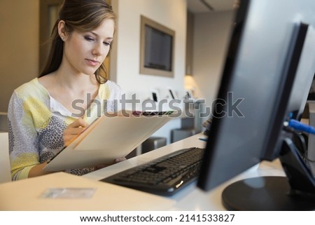 Receptionist writing on medical record at front desk