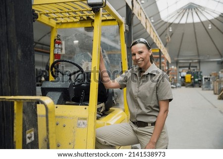Portrait of confident worker leaning on forklift