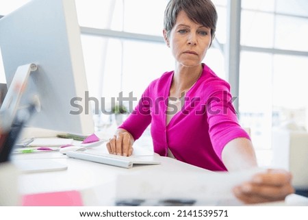 Serious businesswoman reviewing paperwork at desk in office
