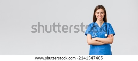 Medical workers, healthcare, covid-19 and vaccination concept. Optimistic confident, professional female nurse or doctor in blue scrubs with stethoscope, cross arms chest and smiling optimistic