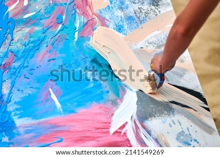 Drip painting expression art on canvas with blue, pink and beige colors, artist art performance. Painter hand with paintbrush drawing drip painting picture, abstract colorful splash and strokes