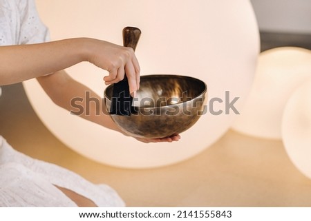 Close-up of a Tibetan singing bowl in your hands - Translation of mantras: transform your impure body, speech and mind into a pure exalted body, speech and mind of a Buddha. Royalty-Free Stock Photo #2141555843
