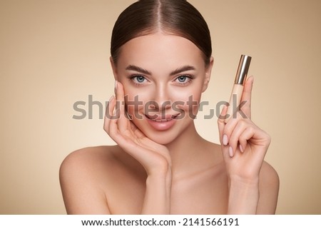 Portrait beautiful young woman with clean fresh skin. Model with foundation makeup bottle. Cosmetology, beauty and spa Royalty-Free Stock Photo #2141566191