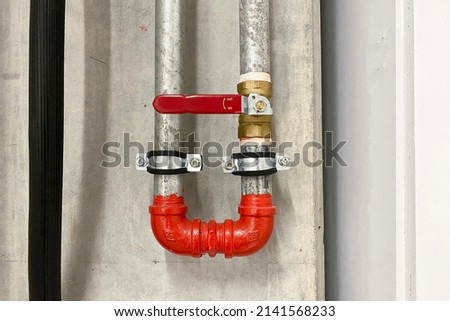 Steel pipe and valve of the hydrant water hoses and fire extinguish equipment on concrete wall.