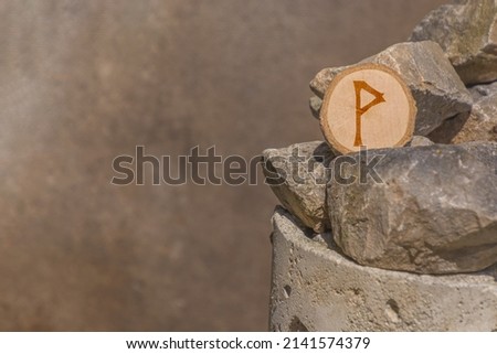 close-up shot of a wooden piece with a Norse rune engraved on it, specifically the wunjo character