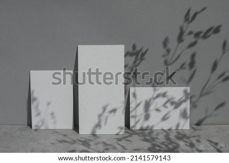Empty white wedding invitation set mock up with soft leaves shadows on grey background. 
