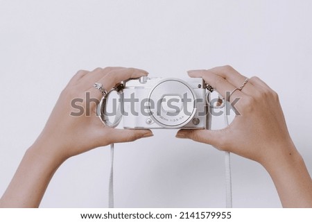 Young girl hands with rings on fingers and manicured nails is holding camera. Mock up and copy space for electronics. 