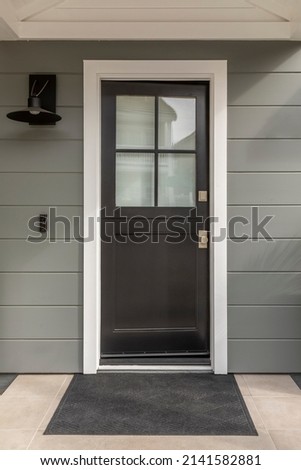 Brown front door, with four pane window, a door mat that is black. Royalty-Free Stock Photo #2141582881