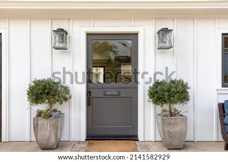 Black front door, front door of a house adorned two potted plants. Royalty-Free Stock Photo #2141582929
