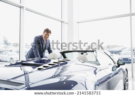 Man looking at convertible in car dealership showroom