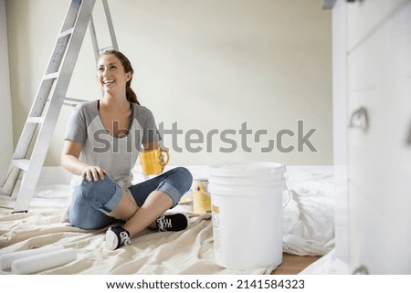 Smiling woman drinking coffee on paint drop cloth