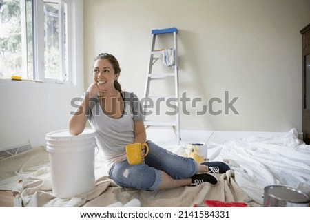 Smiling woman drinking coffee on paint drop cloth