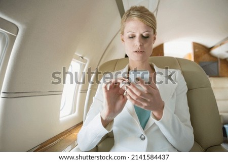 Businesswoman text messaging on corporate jet