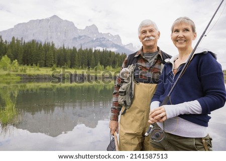 Older couple fishing in still lake