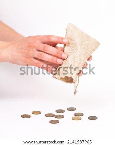 in a small bag standing on a white background, the hand shakes out, pours out, takes out coins. close-up. Russian money. The idea is enrichment, increase in profits