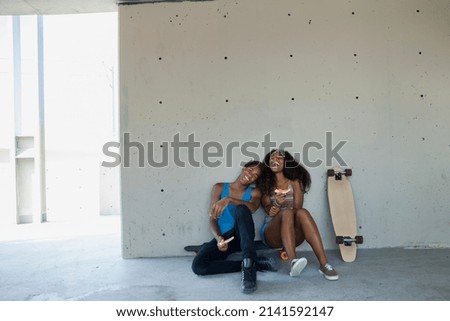 Teenage couple laughing against wall