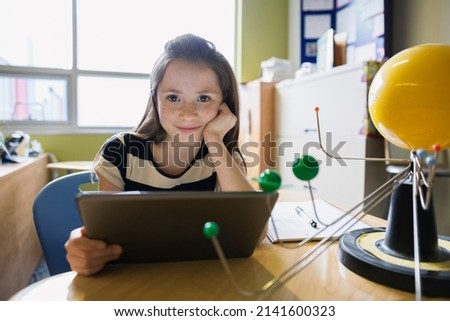 Portrait of smiling elementary student using digital tablet