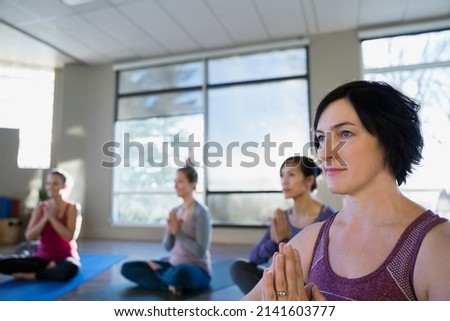 Women with hands at heart center yoga class