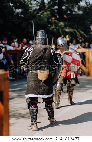 Two knights, warriors fight on the battlefield in armor with a sword in hand in the middle ages in the war.