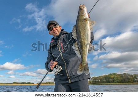 Success zander fishing. Happy fisherman with big walleye fish trophy at lake Royalty-Free Stock Photo #2141614557
