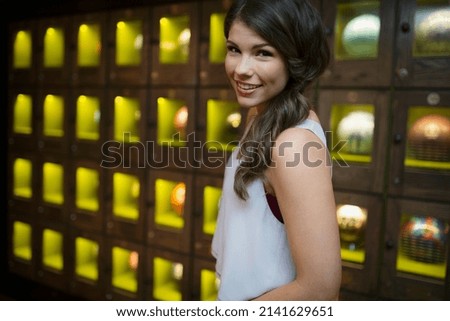 Portrait smiling young woman near bowling ball lockers