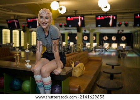 Portrait smiling young woman at bowling alley
