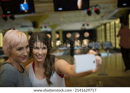 Friends taking selfie with camera phone bowling alley