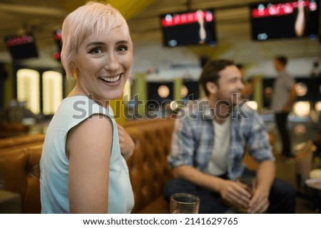 Portrait smiling young woman hanging out bowling alley