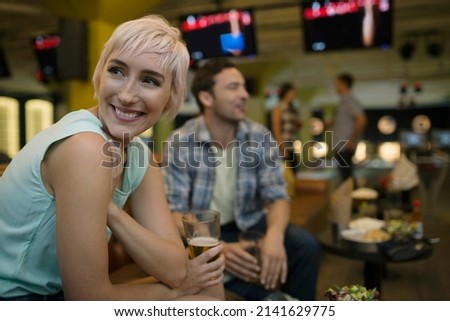 Smiling young woman with friends at bowling alley