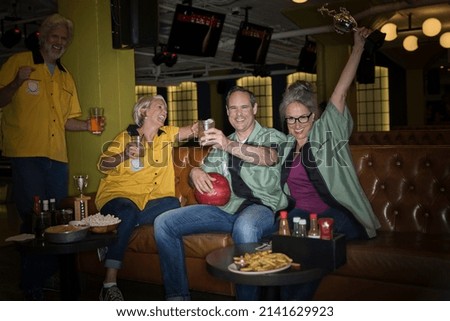 Enthusiastic friends in bowling shirts celebrating bowling alley
